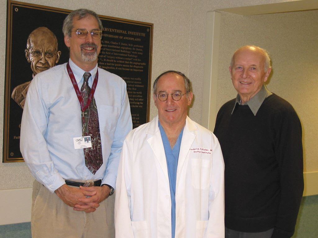Three Dotter Interventional Institute directors: Dr. John Kaufman, the current director; Dr. Frederick Keller, past director; and Dr. Josef Rösch, founding director; in front of a plaque depicting Dr. Charles T. Dotter.